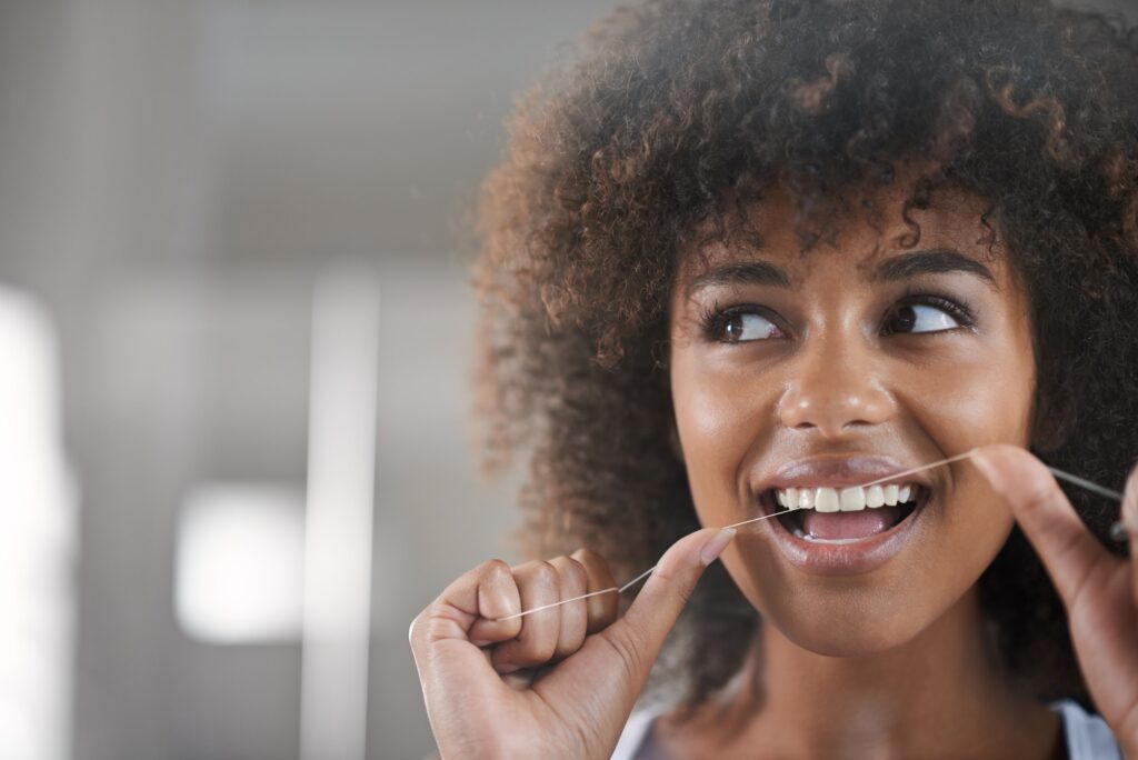 Shes big on dental hygiene. Shot of a young woman flossing her teeth in the mirror.